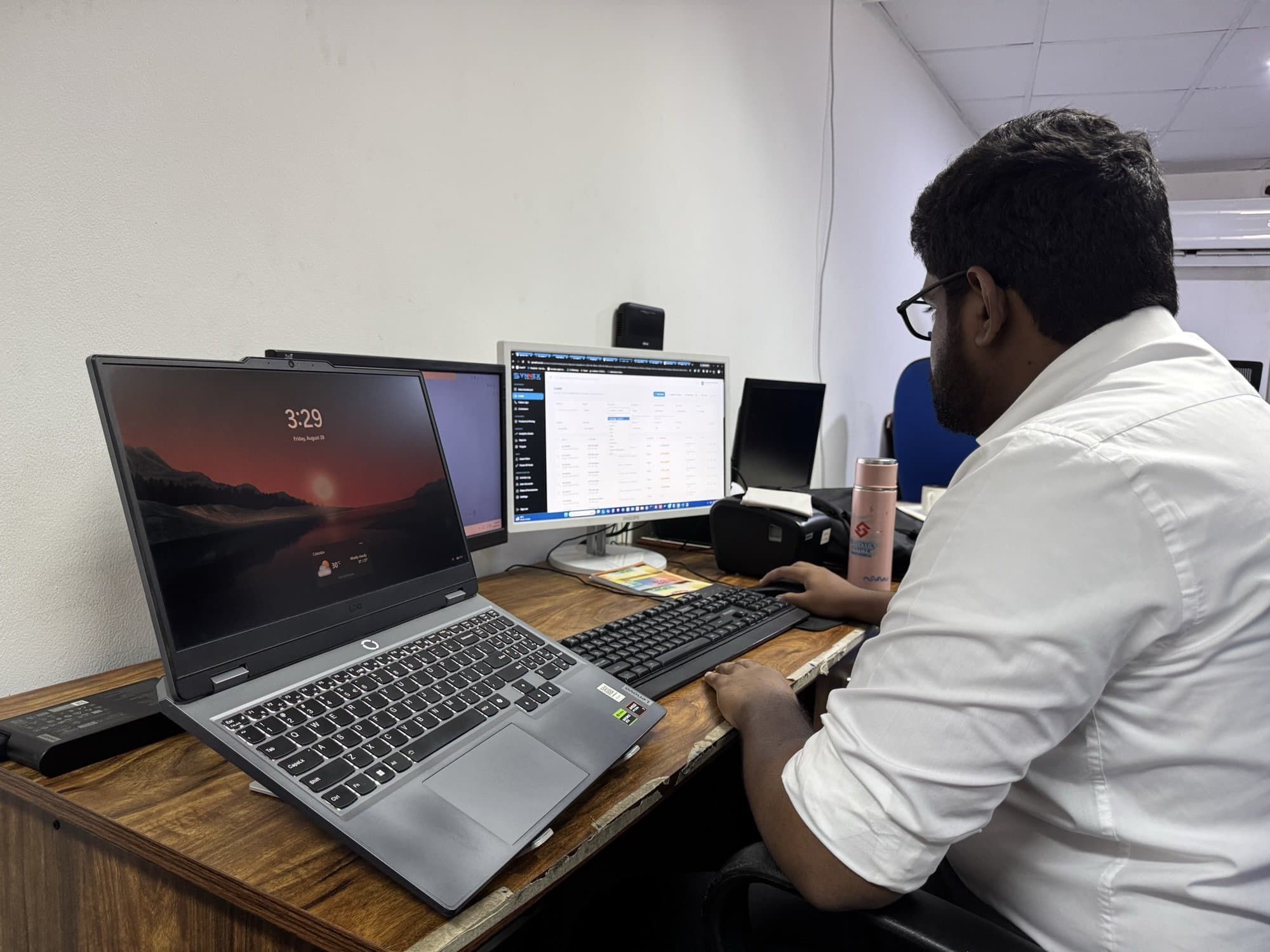 A Synco team member working across dual monitors in the Colombo office